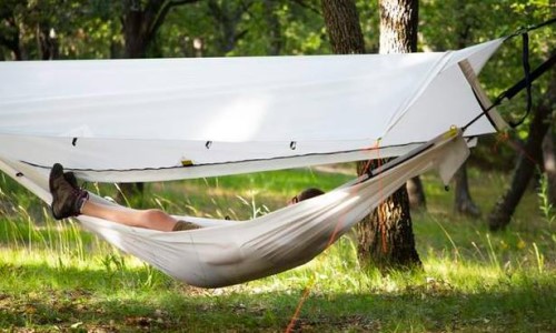 Tienda Beluga 6‑en‑1 configurada como hamaca en un entorno forestal