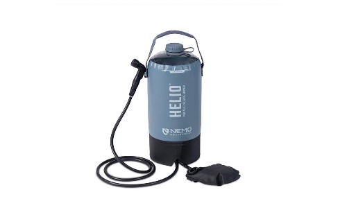 Ducha portátil NEMO Helio en uso con bomba de pie en una zona de acampada