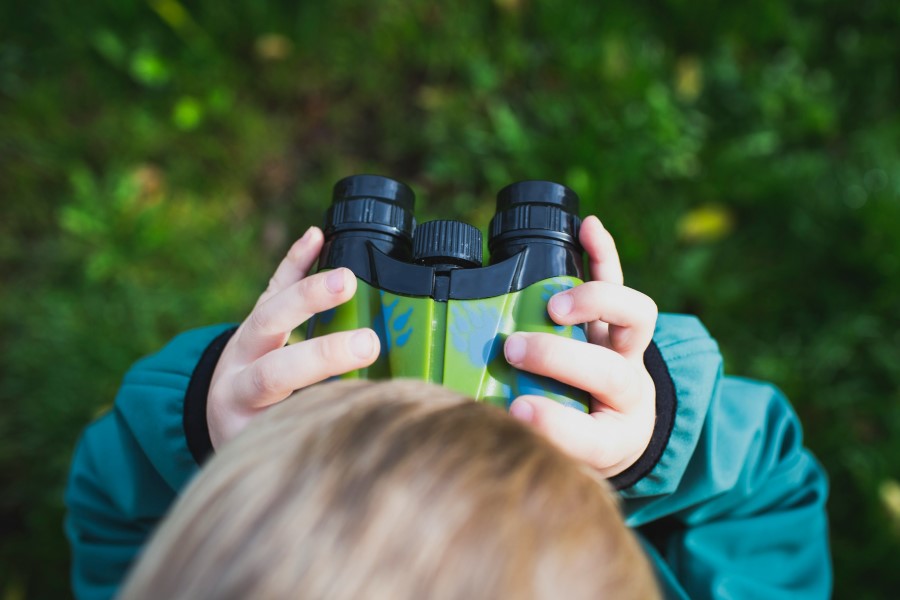 niño observando la naturaleza con prismáticos infantiles
