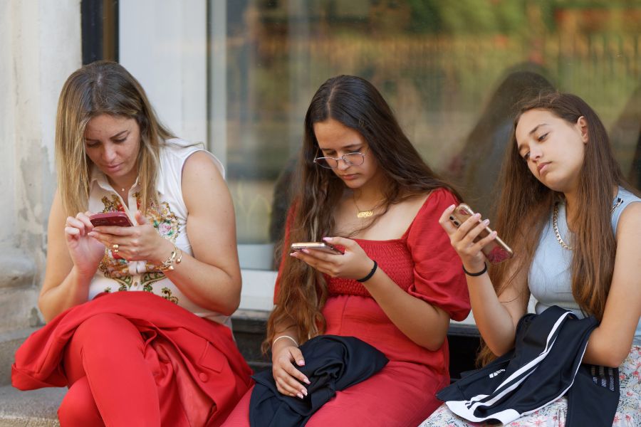 tres personas mirando su teléfono sin hablarse en un evento familiar